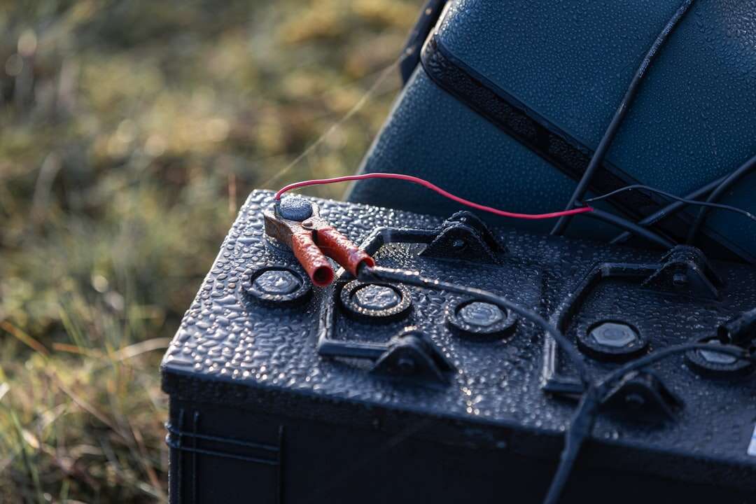 A lithium battery connected to a solar panel outdoors in the grass, the field charging setup that needs cold weather care