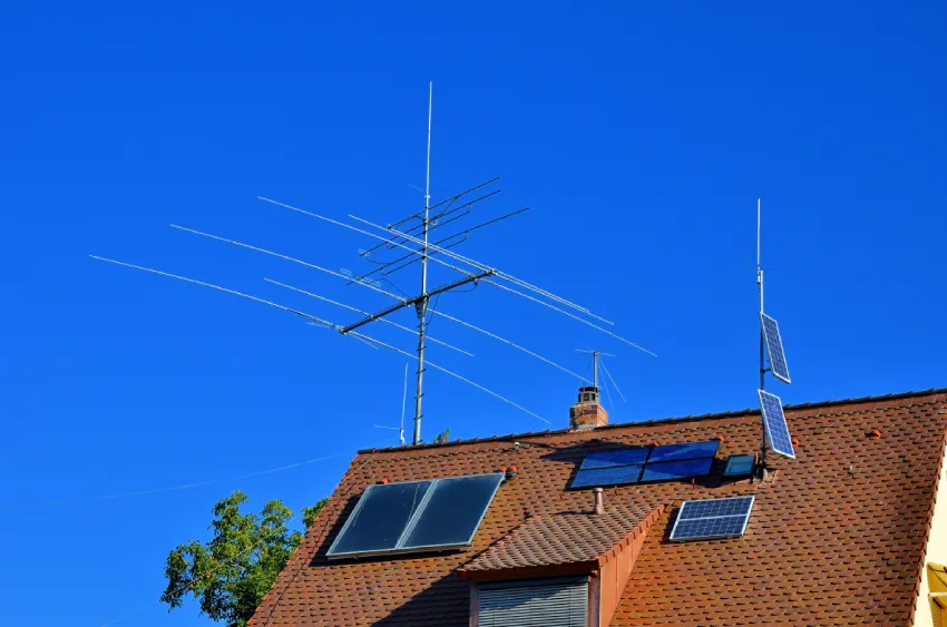A rooftop mounted HF beam antenna and vertical above the tiled roof of a house, the kind of installation an RF exposure evaluation has to account for because people live directly underneath it